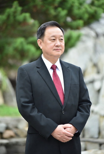 一位穿西装的华人老板站在花园里。