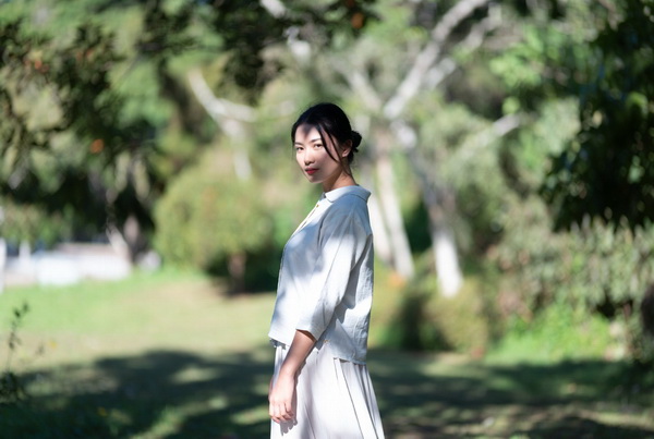 一位艺术体操运动员站在树影中……