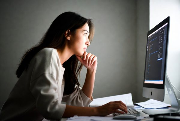 一个女生正坐在电脑前思考。