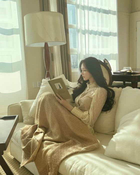 一个女生正坐在沙发上看书。